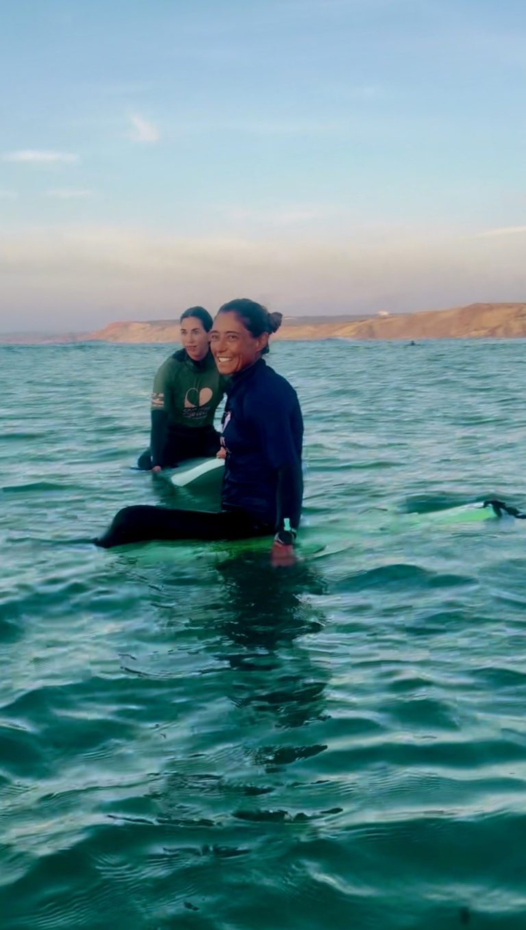 Inês Tralha com uma aluna no oceano durante uma sessão de surf