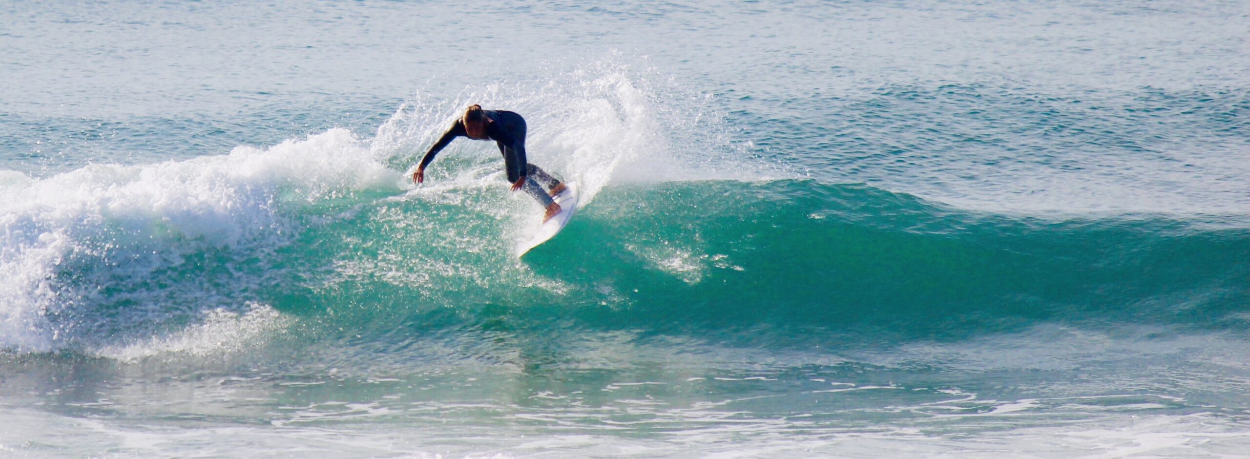 Surfer performing a manoeuvre on a green wave with a fiberglass board