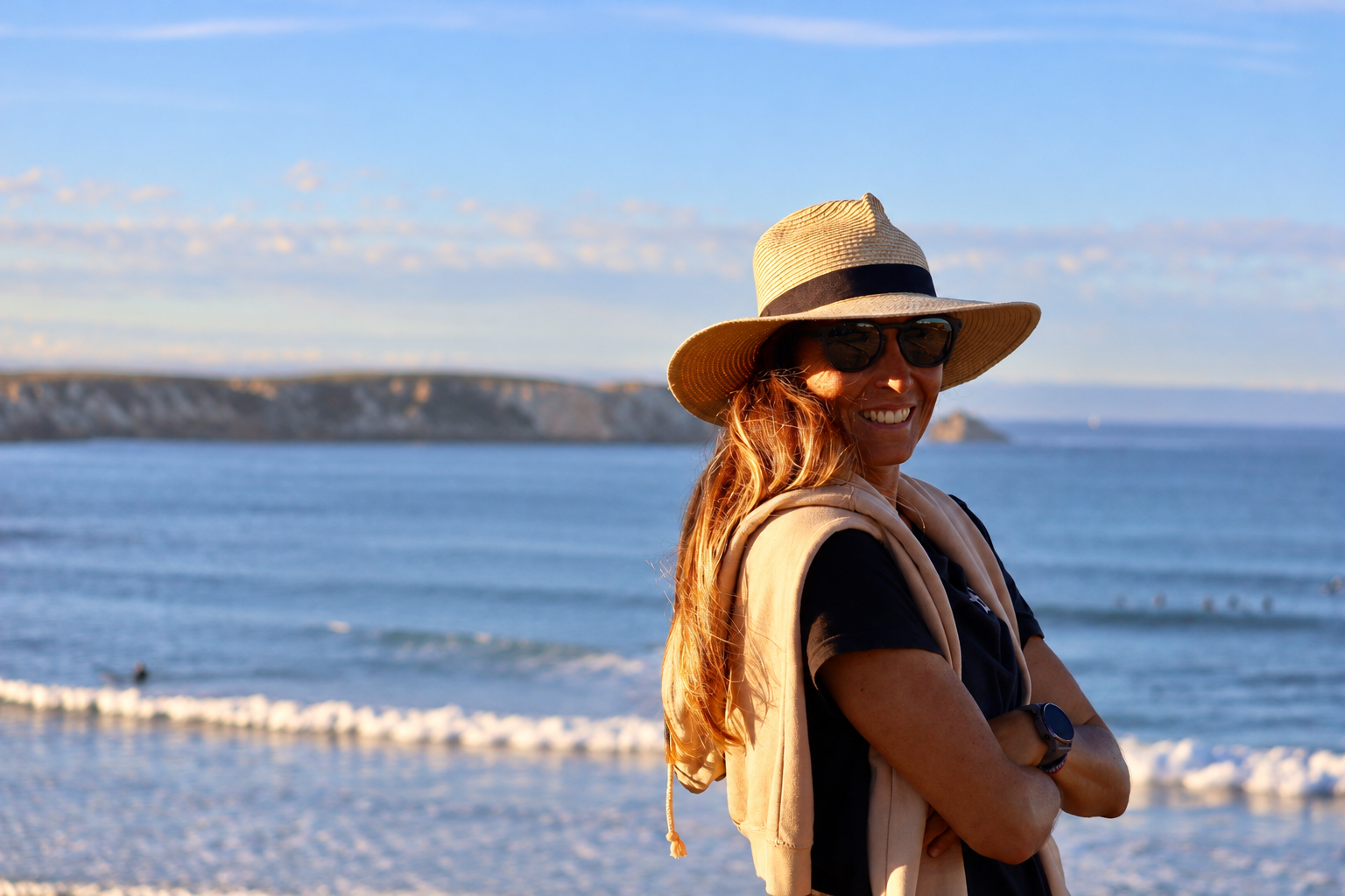 Inês Tralha, de chapéu e braços cruzados, junto ao mar